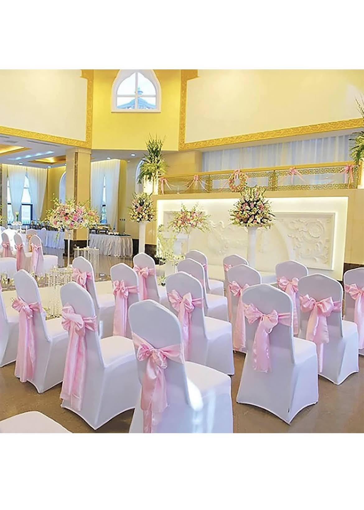 Event venue styled with white chair covers and soft pink bows